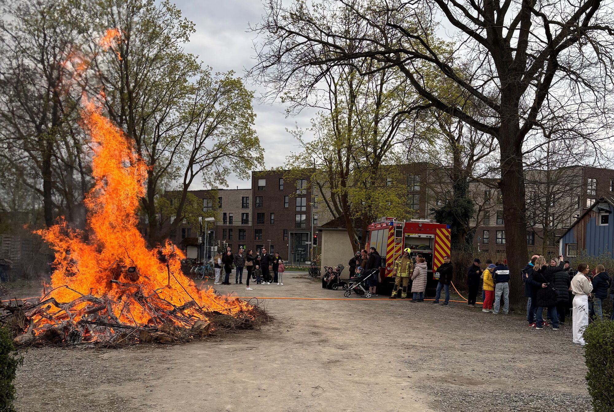 Brennendes Osterfeuer auf dem Parkplatz, im Hintergrund ein Fahrzeug der Feuerwehr